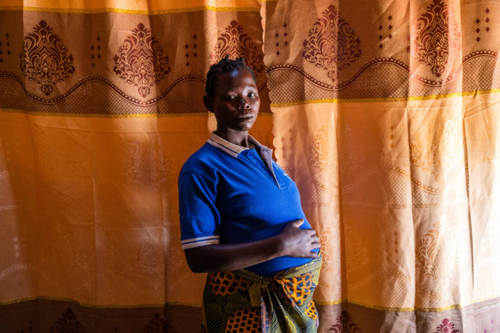 Pregnant woman standing in front of a curtain.