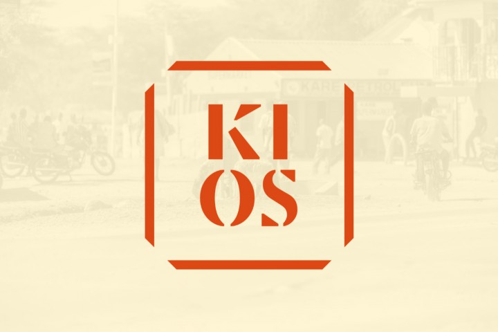 KIOSin logo vaaleankeltaisella taustalla, jonka alta himmeästi näkyy läpi kaupunkimaisemaa