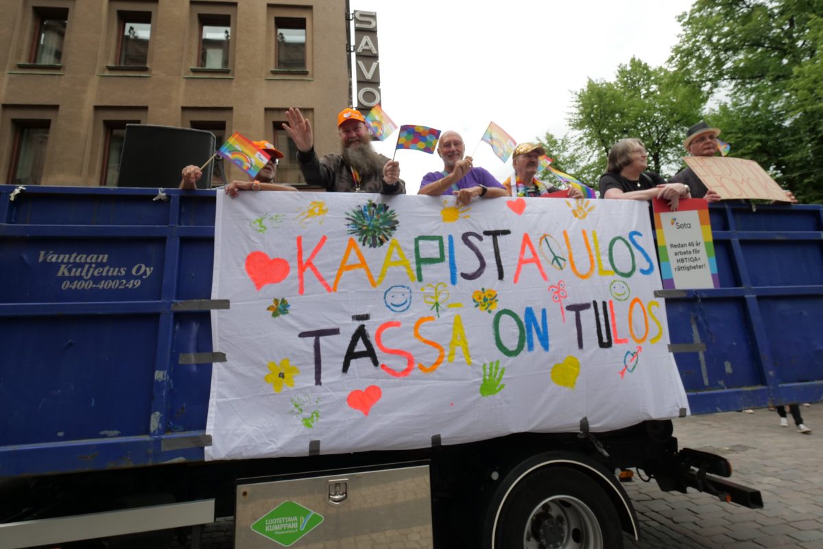 A truck with people in and a banner on the side