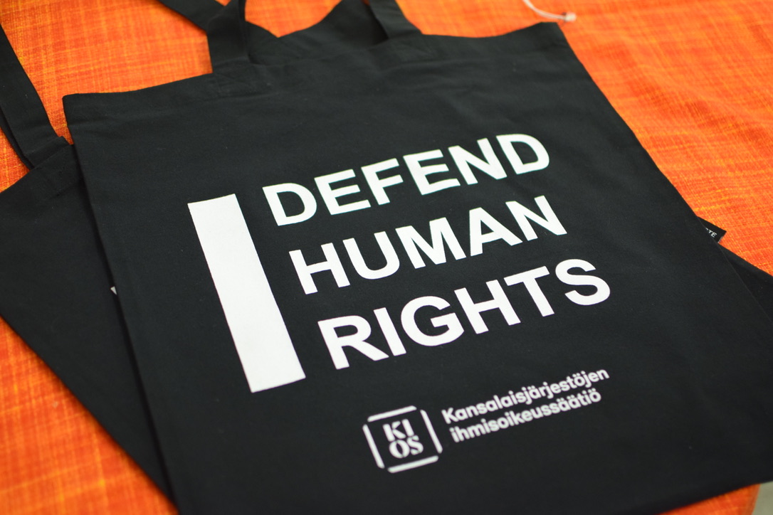 A tote bag with a text "I defend human rights" and KIOS logo