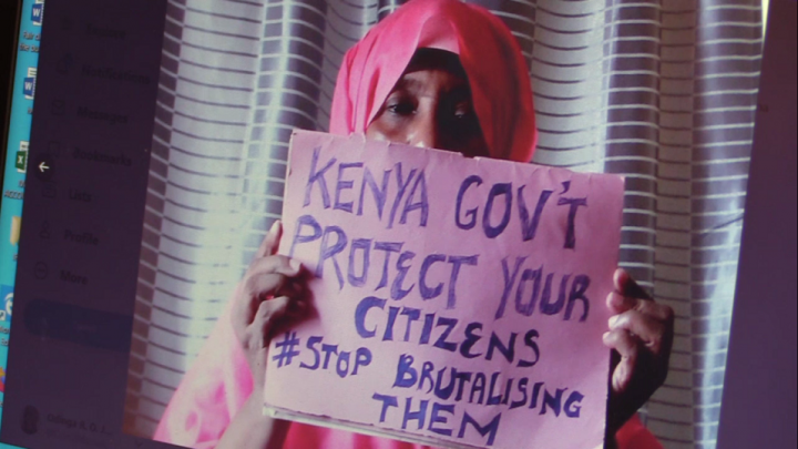 Woman holding a poster saying ”Kenya government protect your citizens #Stop brutalising them”